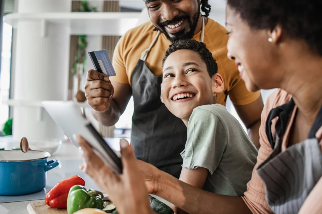 Country-Bank-family-in-kitchen-cooking-using-debit-card-for-online-purchase