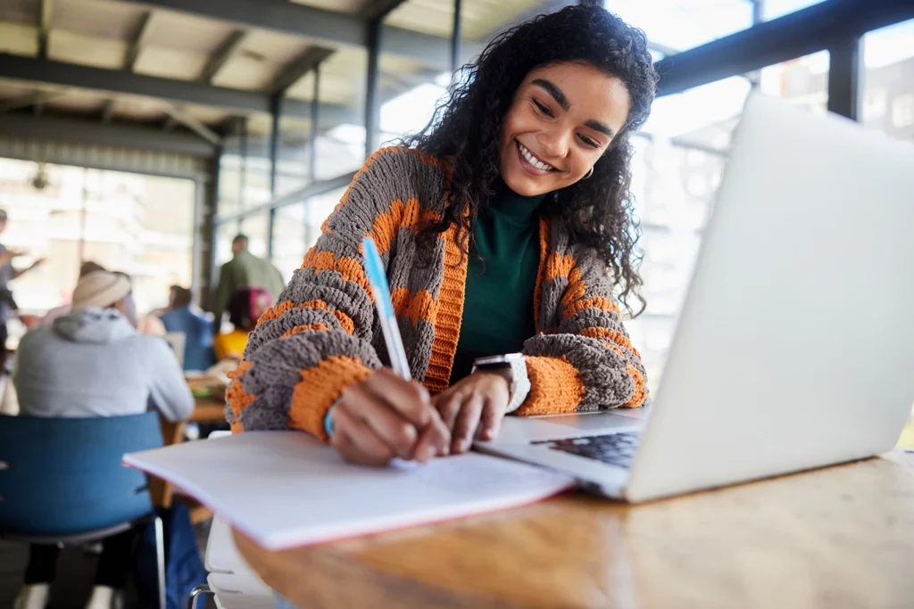 Country-Bank-female-student-sitting-table-with-computer-writing-on-notepad