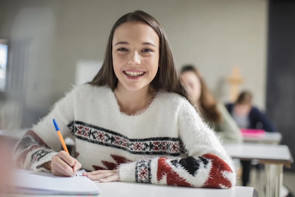 Country-Bank-happy-girl-sitting-at-school-desk-writing-in-a-notebook