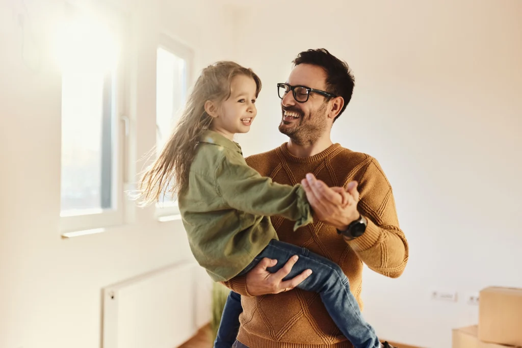 Country-Bank-happy-man-holding-happy-daughter-in-their-home-next-to-window