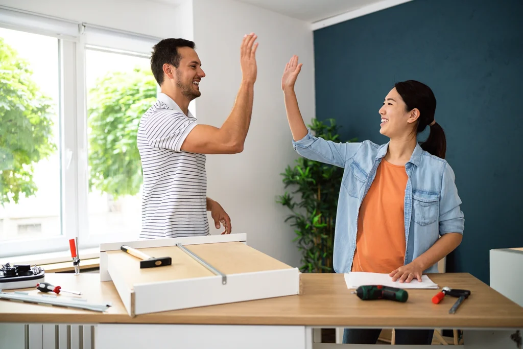 Country-Bank-happy-young-couple-high-fiving-while-assembling-office-furniture