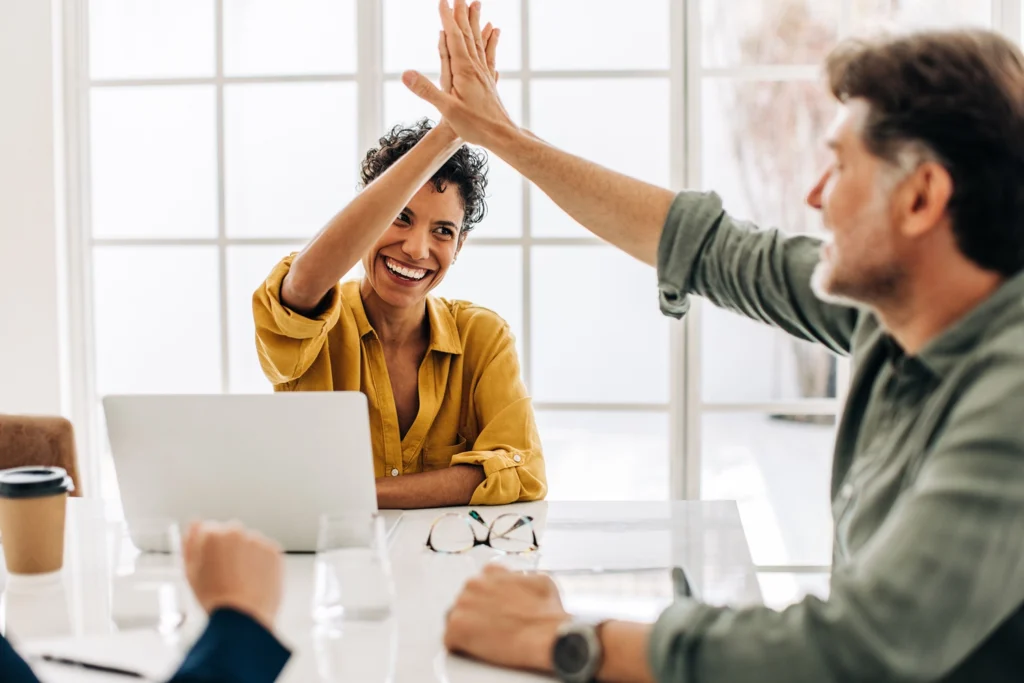Country-Bank-man-and-woman-at-office-conference-table-high-five-each-other