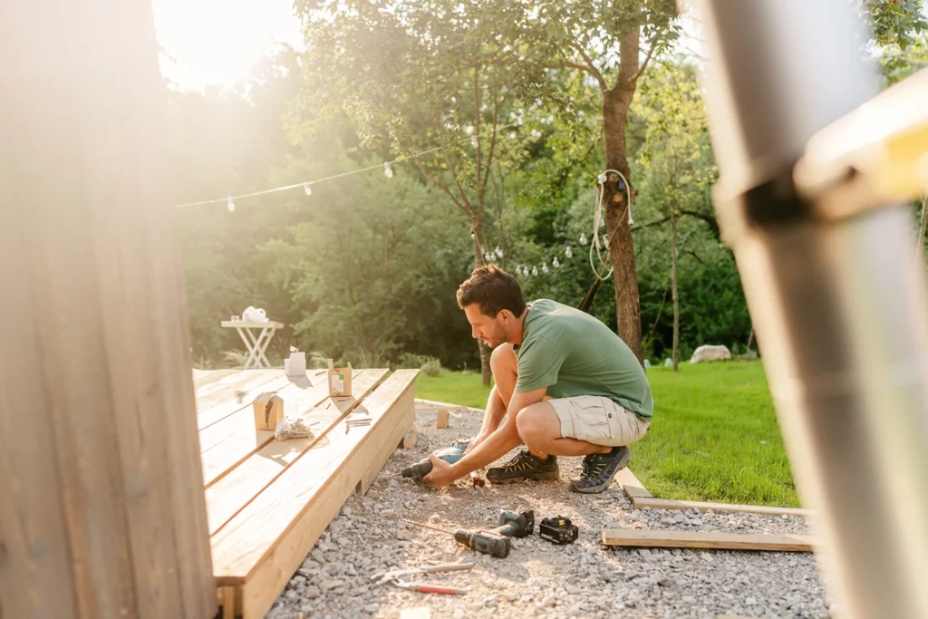 Country-Bank-man-in-backyard-bending-down-to-drill-deck