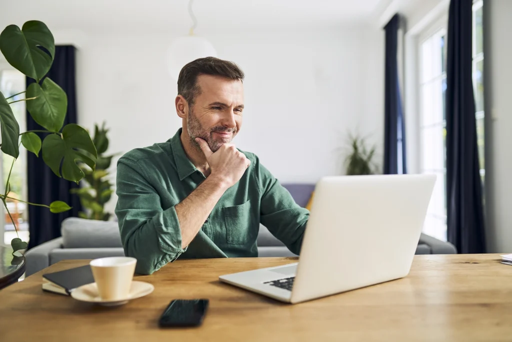 Country-Bank-man-sitting-at-computer-looking-happily-at-his-bank-accounts