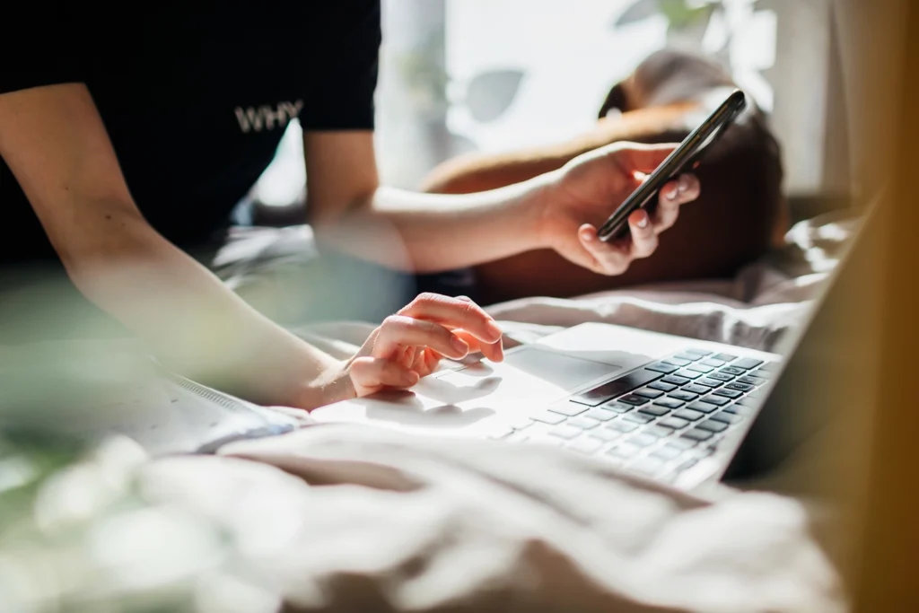 Country-Bank-person-holding-phone-while-typing-into-computer
