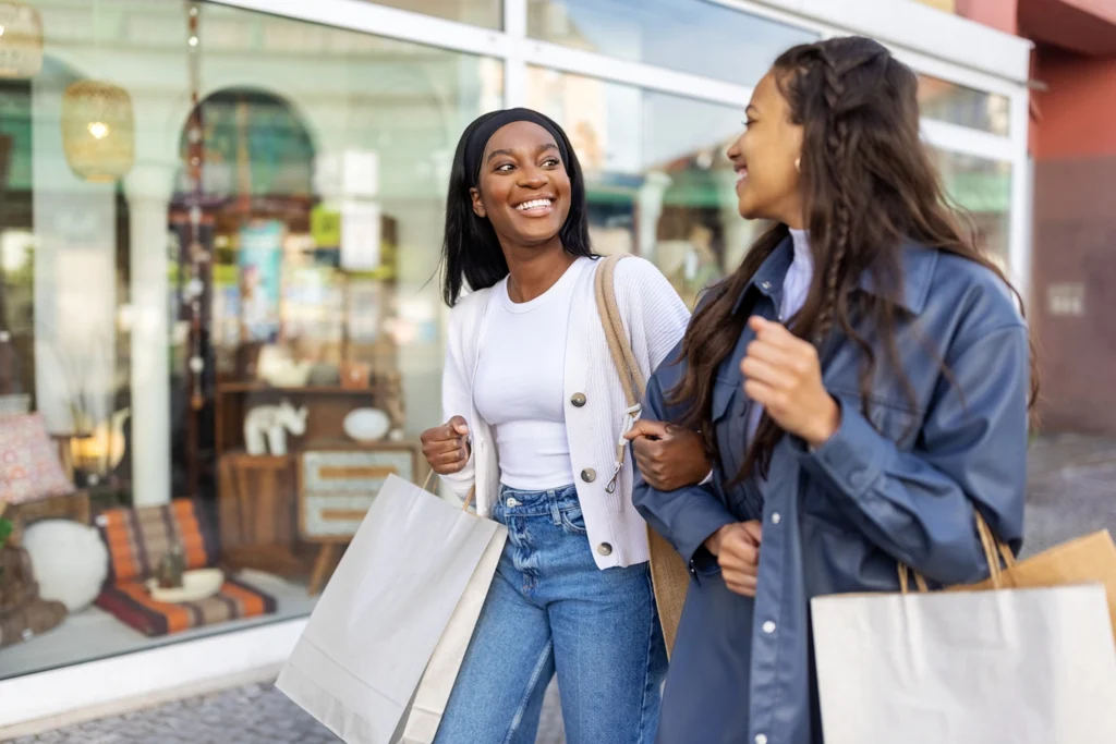 Country-Bank-two-young-women-carrying-shopping-bags-walking-past-storefront
