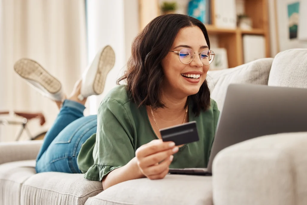 Country-Bank-woman-on-couch-looking-at-computer-holding-out-her-credit-card